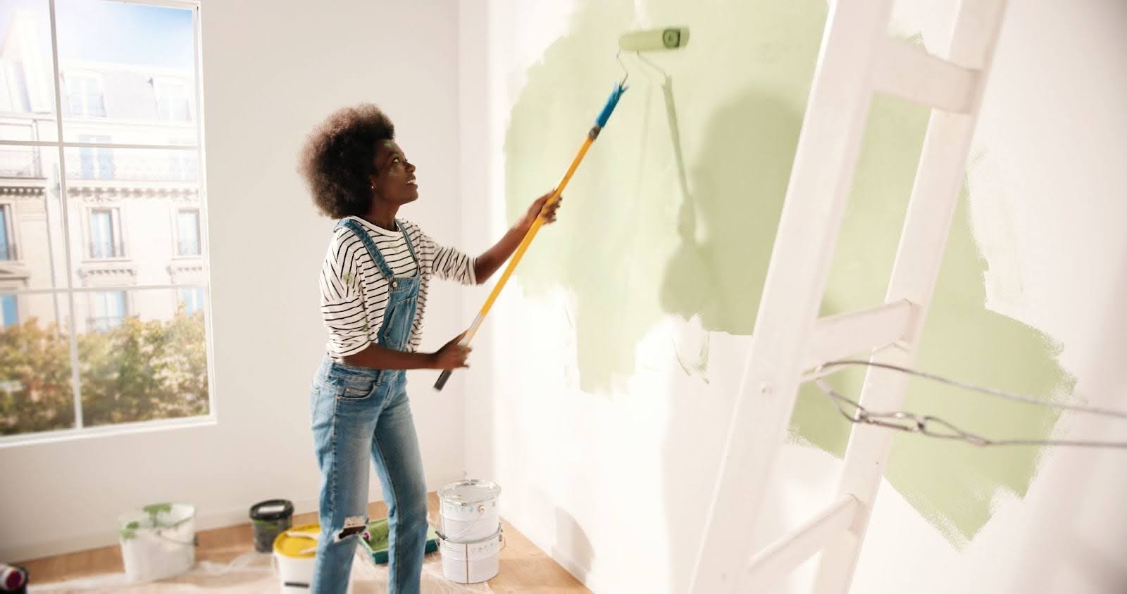 A woman painting the interior of a house green.